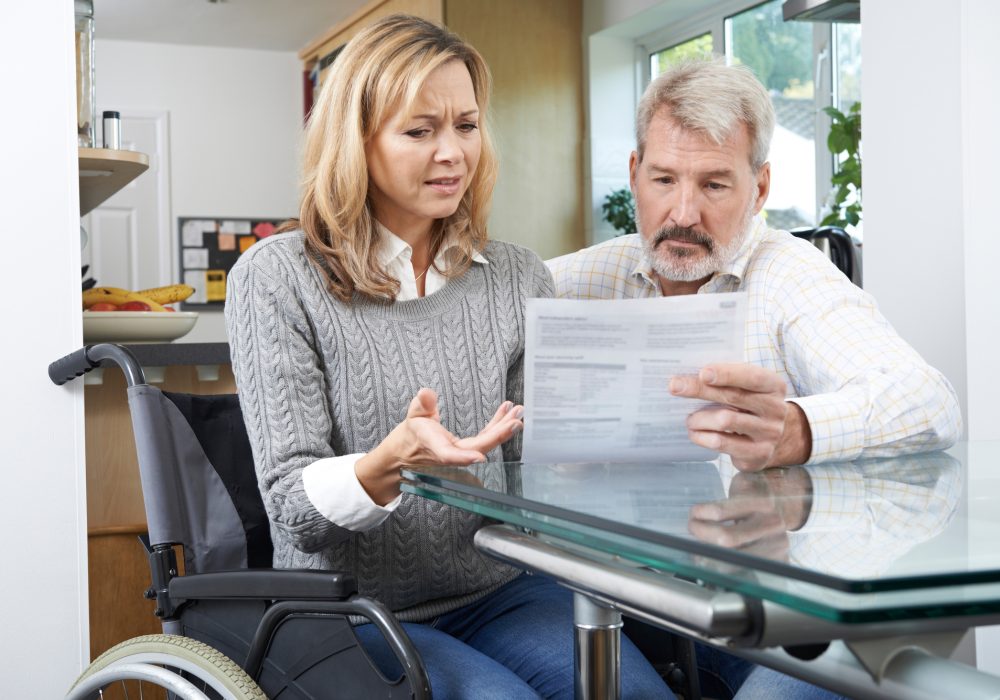 Frustrated Couple With Woman In Wheelchair Reading Letter